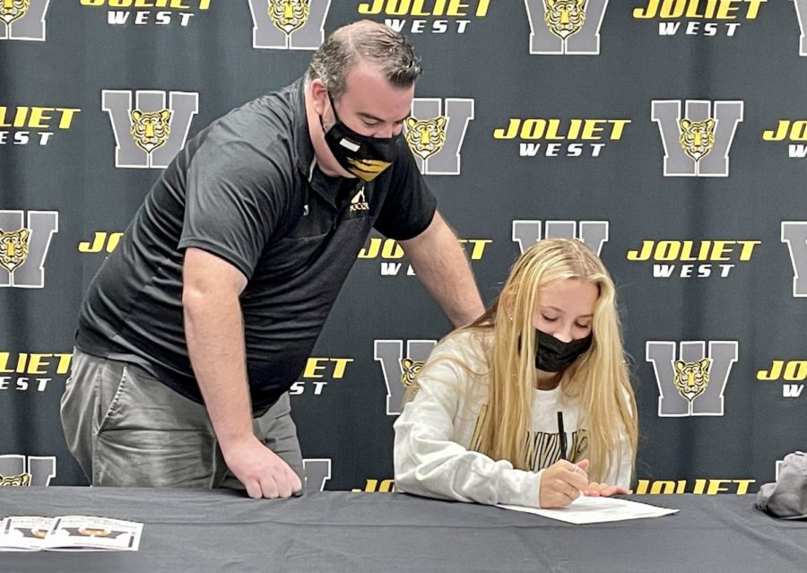 Girls soccer coach Mr. Stewart watches Joslyn Prosek sign her letter of intent to play for Jacksonville University. Photo courtesy of JTHS 204 on Flickr.
